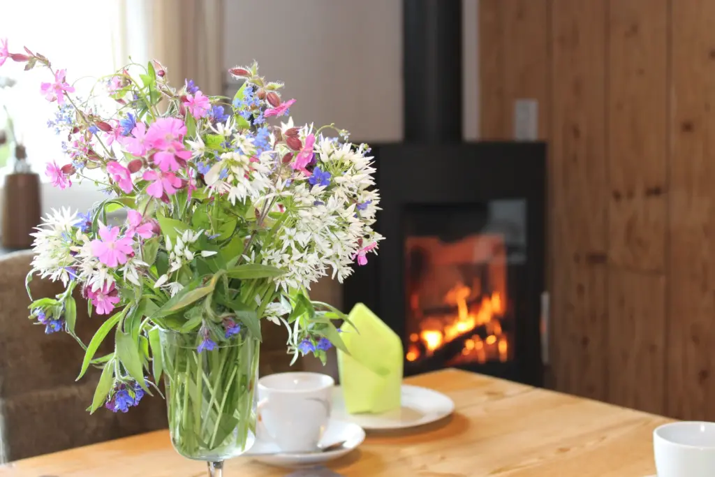 Blumenstrauß auf dem Tisch vor einem brennenden Kamin